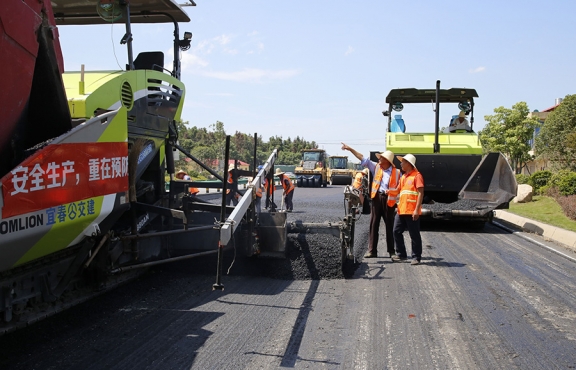 攤鋪機(jī)、壓路機(jī)等設(shè)備緊張有序運(yùn)行，高達(dá)170℃的瀝青混合料炙烤著公路人